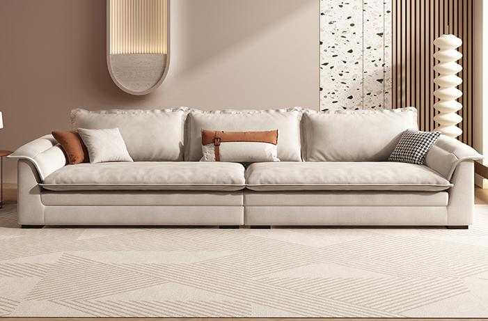 Cat scratching the fabric sofa in a minimalist cream style small-sized living room with a large sofa that is deep and wide and arranged in a straight line.